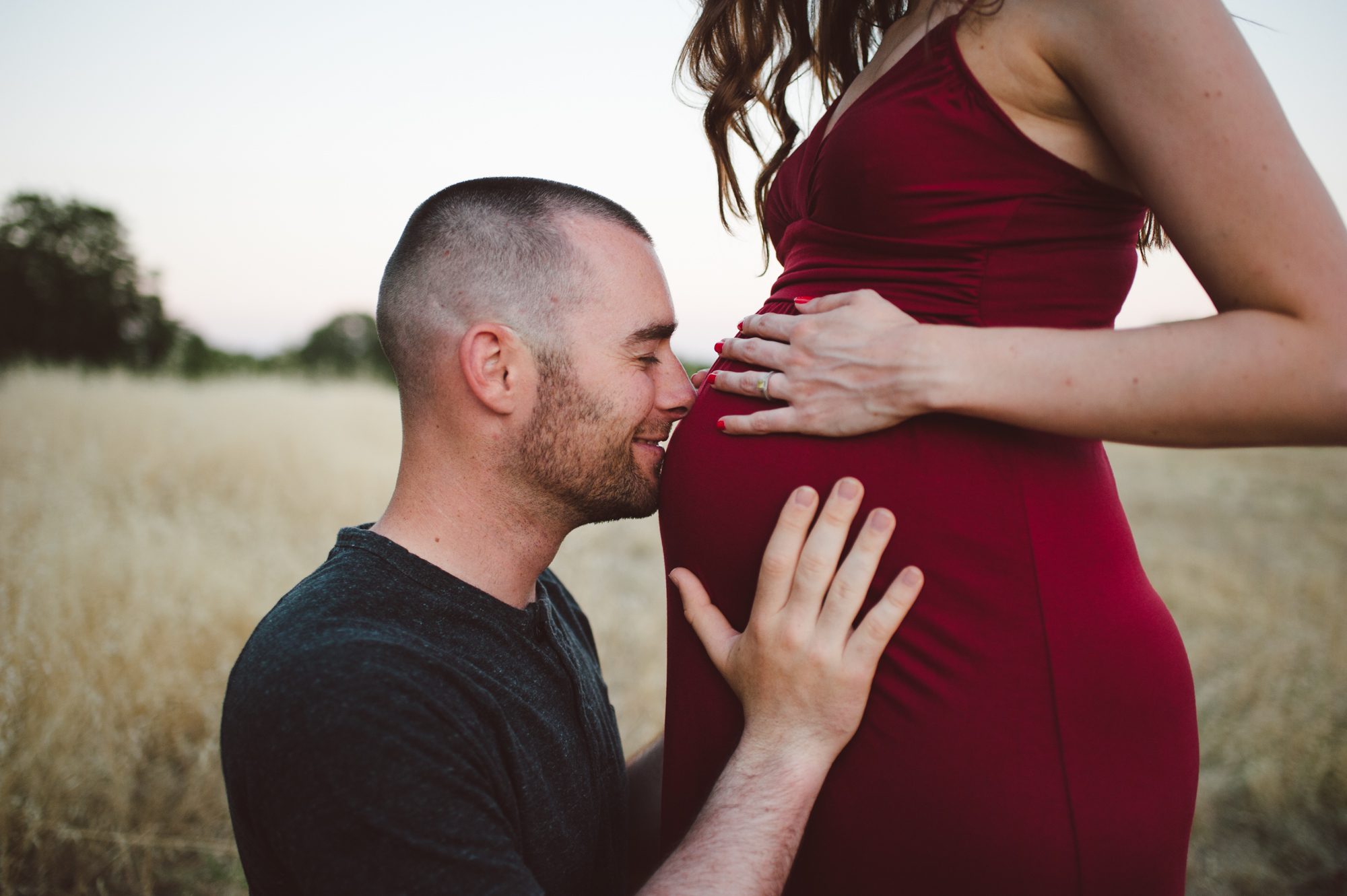 man kisses wife's pregnant belly